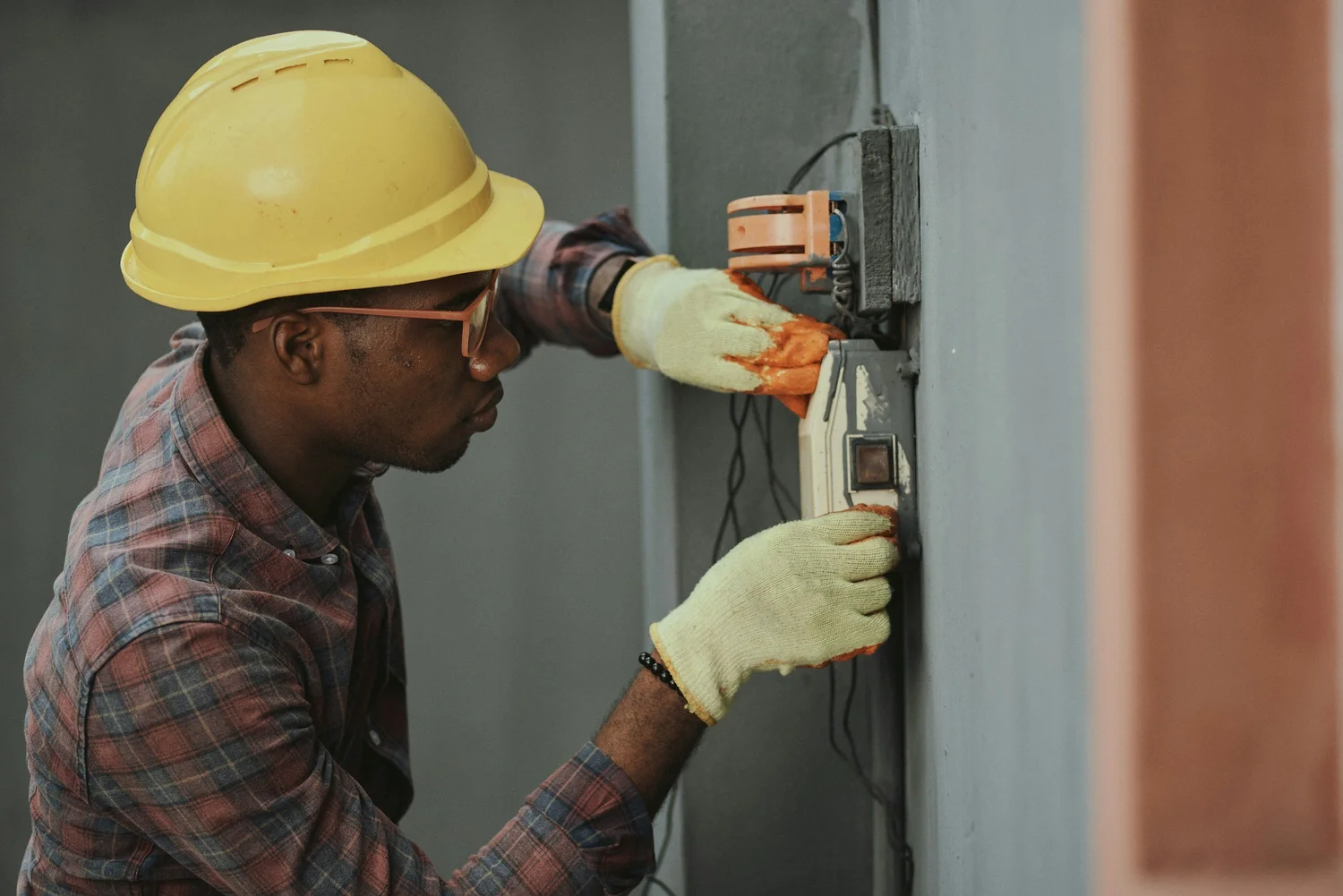 Technician wearing a yellow hard hat working on electrical equipment